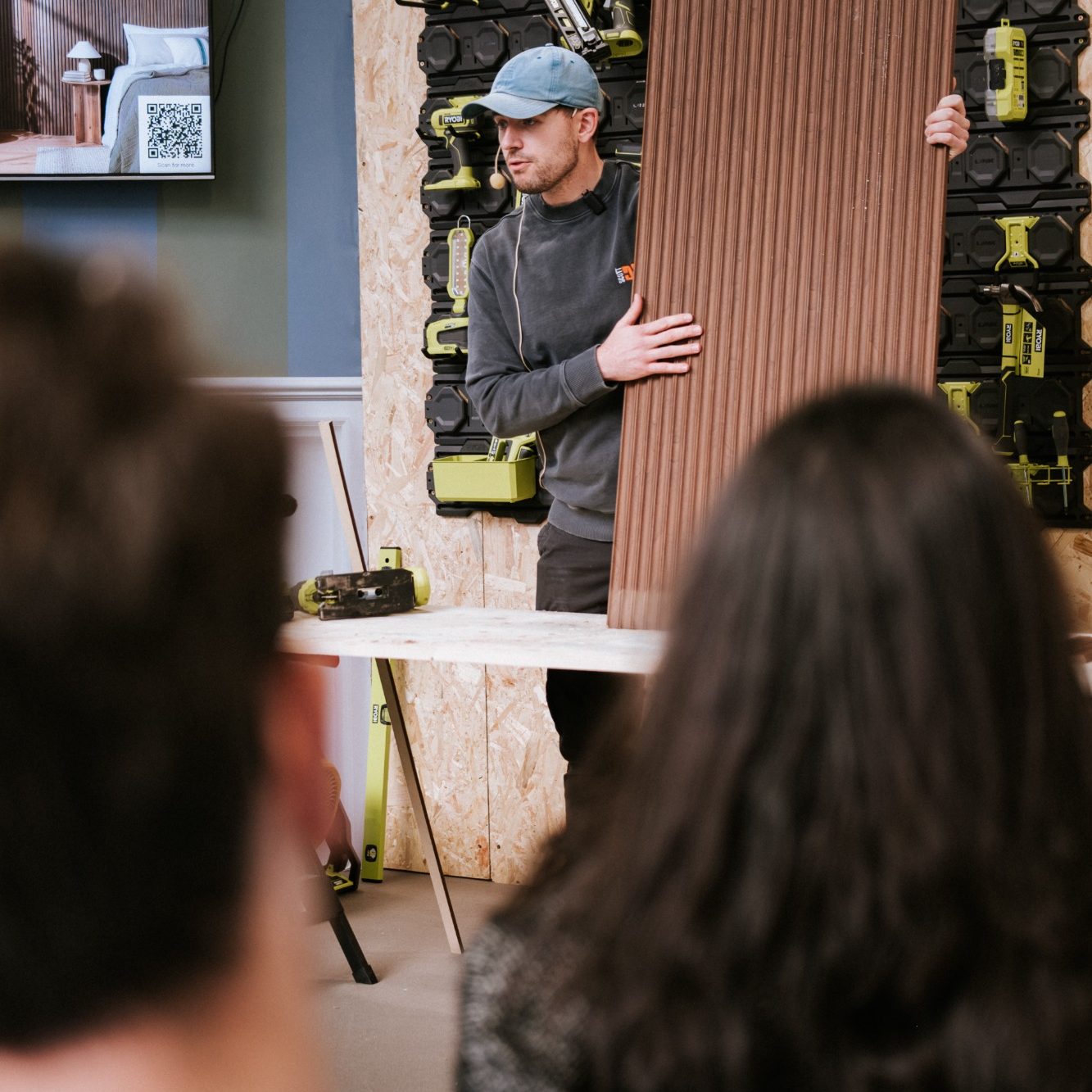 DIY creator Scott holding a fluted wooden wall panel during a presentation at the Ideal Home Show.