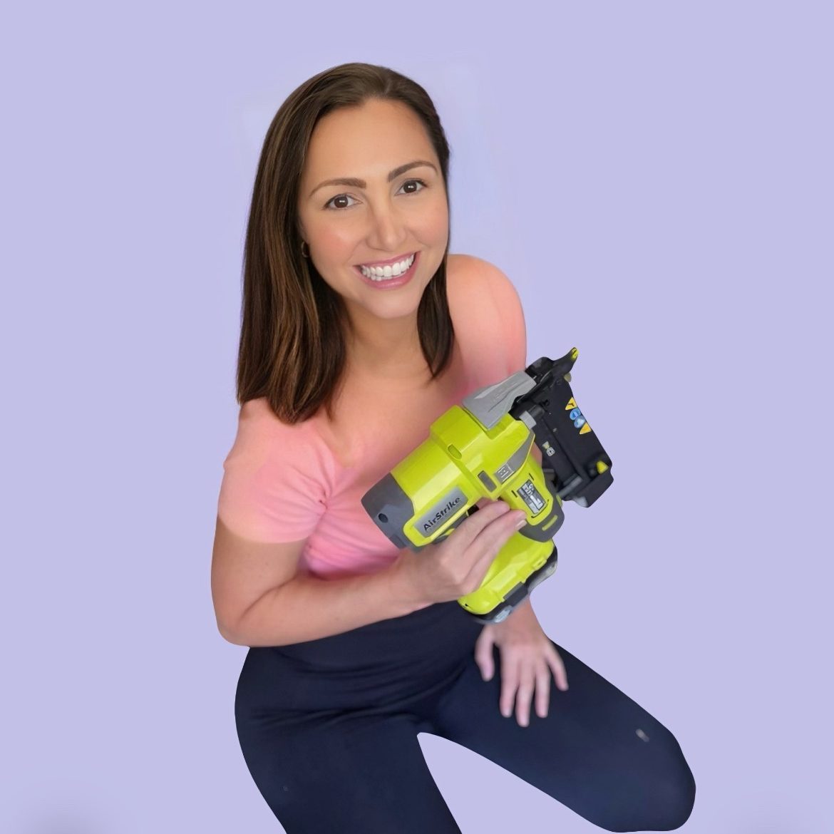 Portrait of Becky Russell smiling on a purple background while holding a bright green power tool.